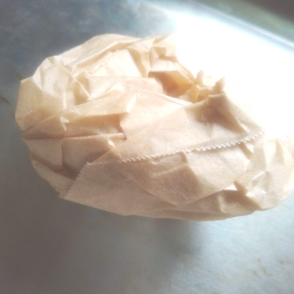 クッキングシートが丸まってケーキの生地が流し入れにくいので、一度クシャクシャに丸めてから広げると真っ直ぐになる裏技の画像
