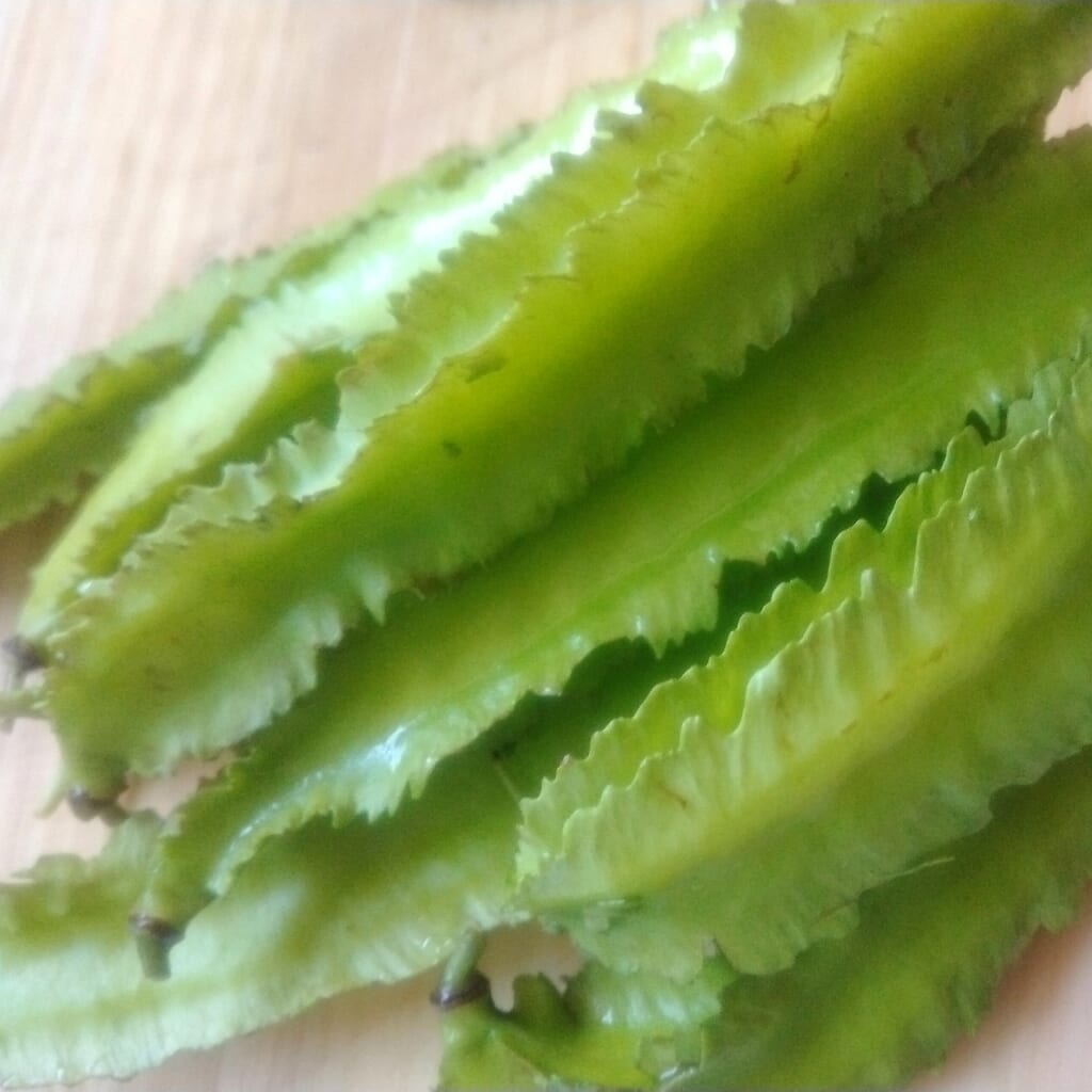 自然栽培の新鮮な四角豆（うりずん豆）をまな板の上に乗せている様子
